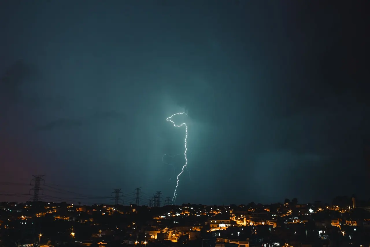 Éclair vert-bleu au-dessus d'une ville sous un ciel d'orage