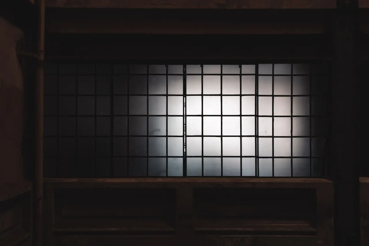 Grande fenêtre à carreaux éclairée de l'intérieur sur un mur sombre la nuit