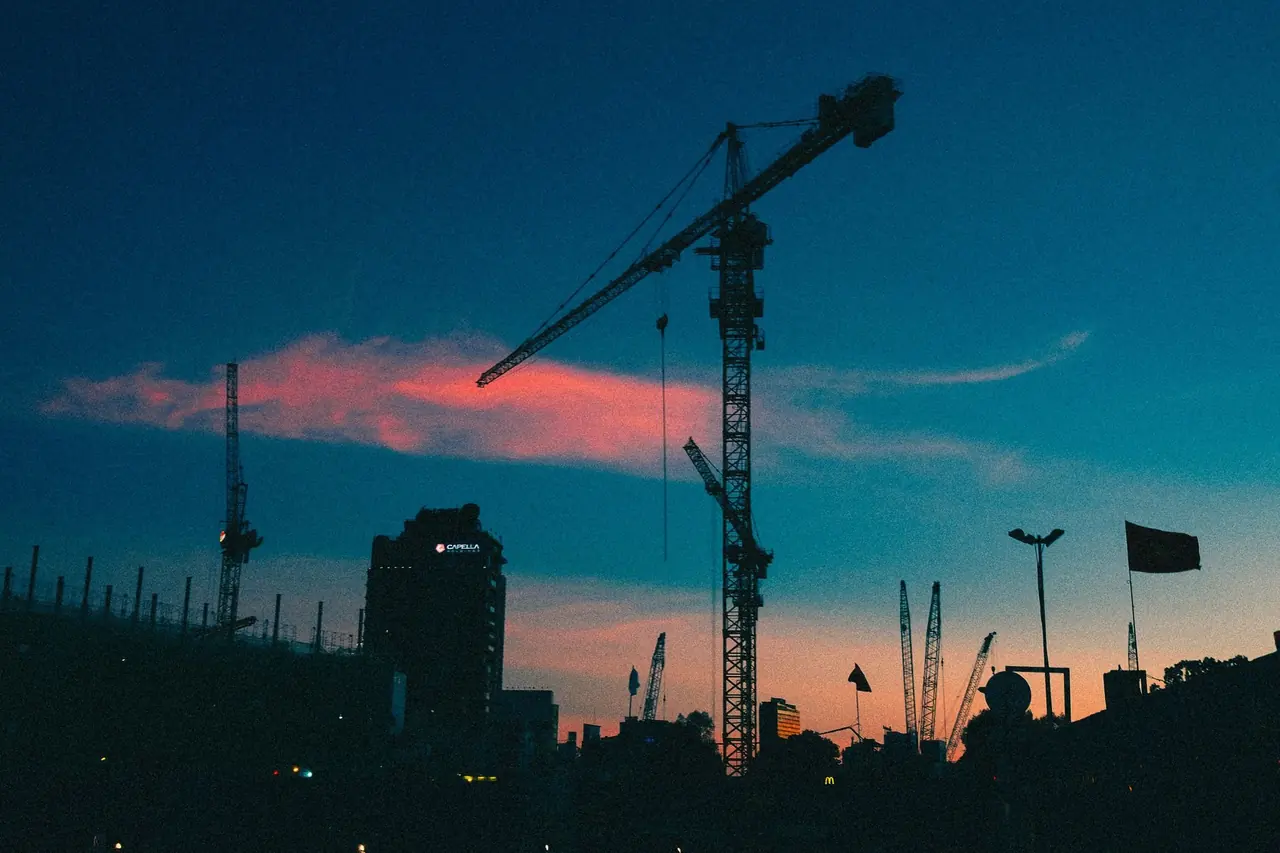 Grue de chantier en silhouette sur ciel turquoise au coucher du soleil